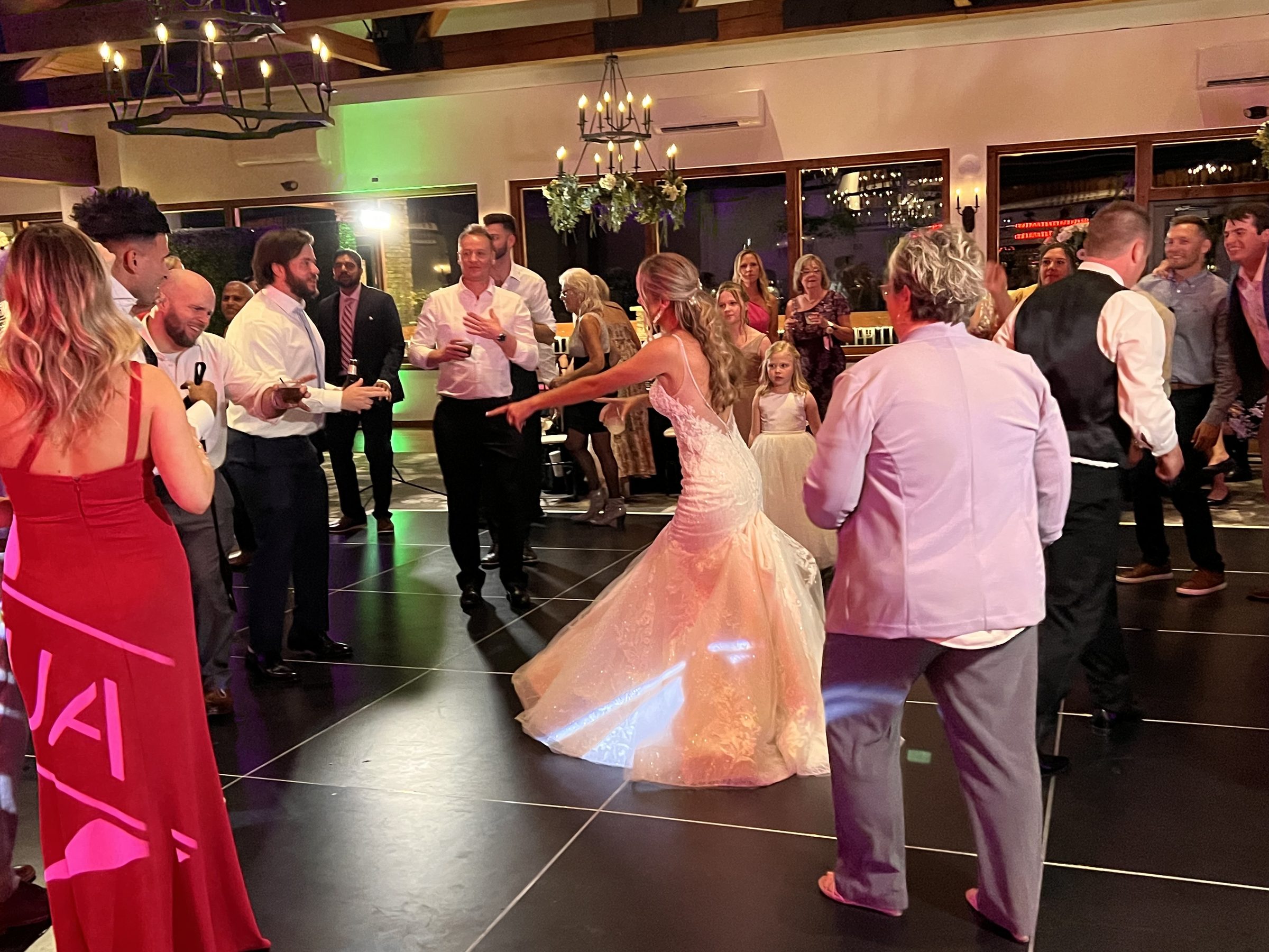 Bride twirls in her gown in the middle of the dance floor as guests cheer her on at a wedding reception