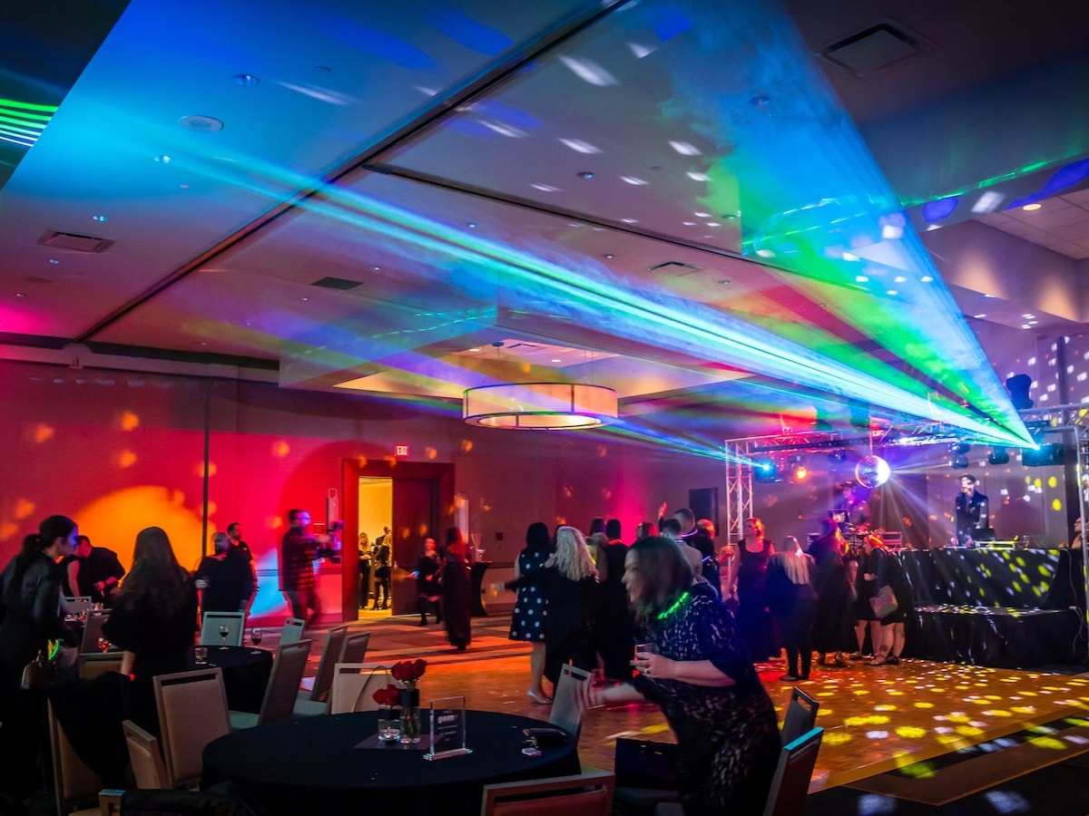 Lasers sweep a hotel ballroom as guests dance beside the truss rig and DJ booth at a company party