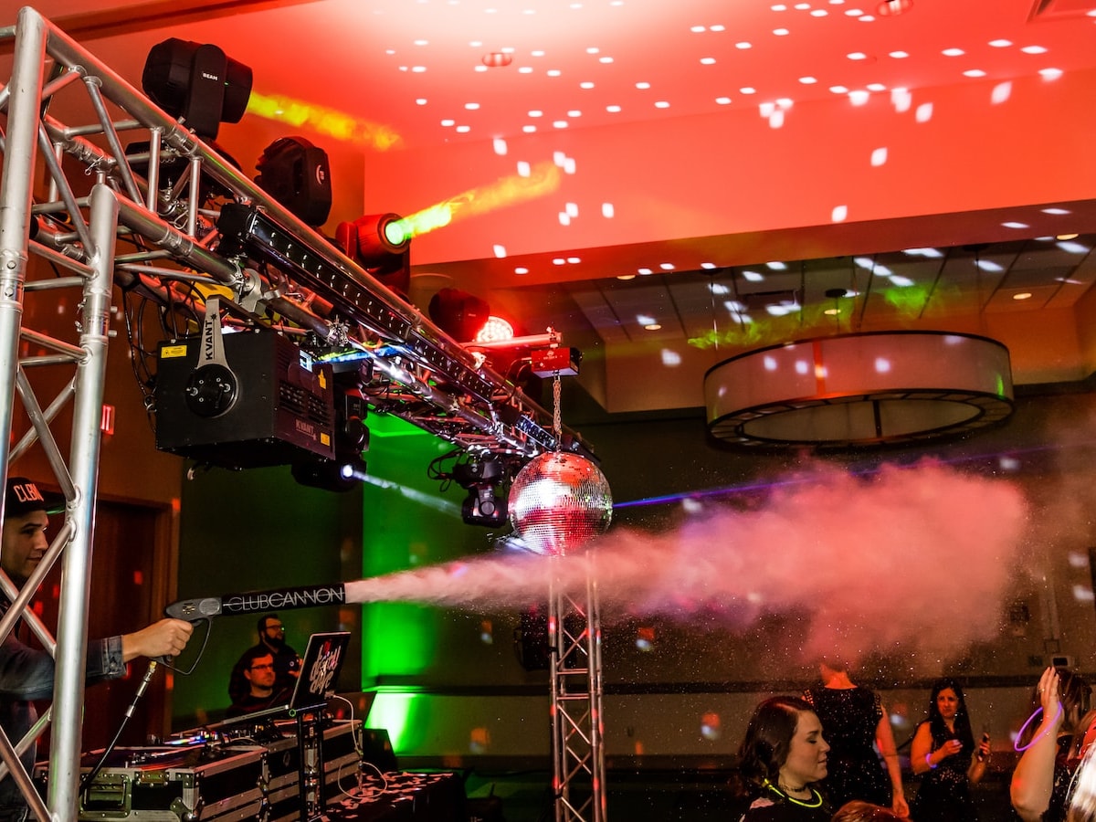A CO2 cannon fires across the dance floor beneath a truss loaded with lasers, moving heads and a mirror ball