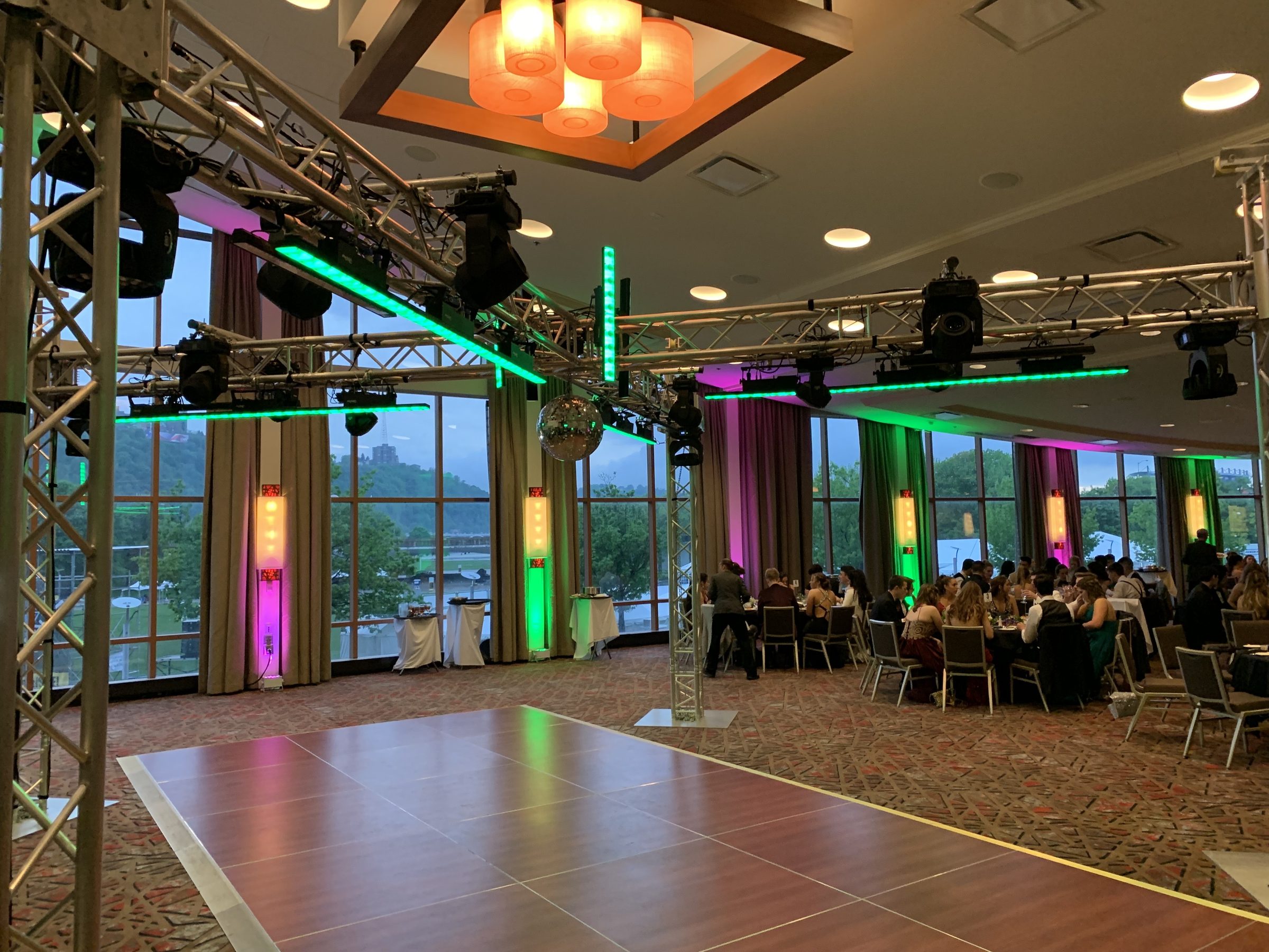 Titanium X rig at a prom: X-shaped truss with moving heads, LED bars and a mirror ball over the dance floor, students at dinner tables